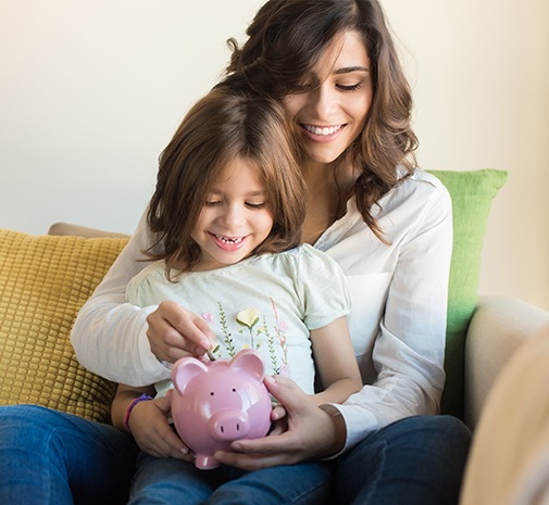 Mother and child placing money in a piggy bank