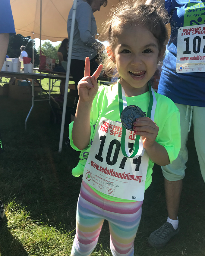 Little girl holding a medal after SEDOL five K event