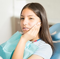 Teen girl with broken tooth holding cheek in pain