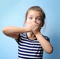 Little girl with lost filling covering her mouth