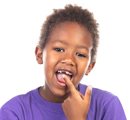 Young child pointing to mouth after tooth extractions