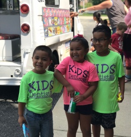 Three smiling children at community event