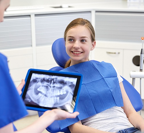 Dentist reviewing young patient's digital x-rays during dental checkup and teeth cleaning
