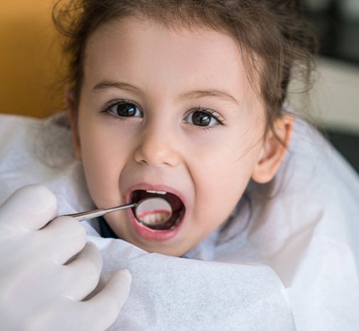 Dentist examining child's smile after tooth colored filling treatment