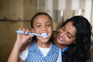 a parent helping a child brush their teeth
