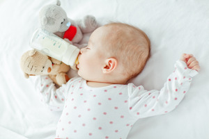 Baby sleeping with a bottle in their mouth