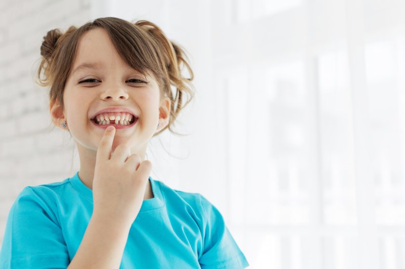 Young child smiling with a missing tooth after baby tooth extraction