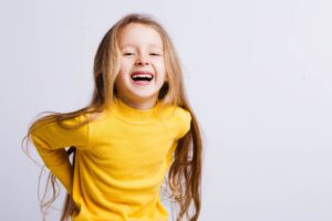 little girl in yellow blouse smiling